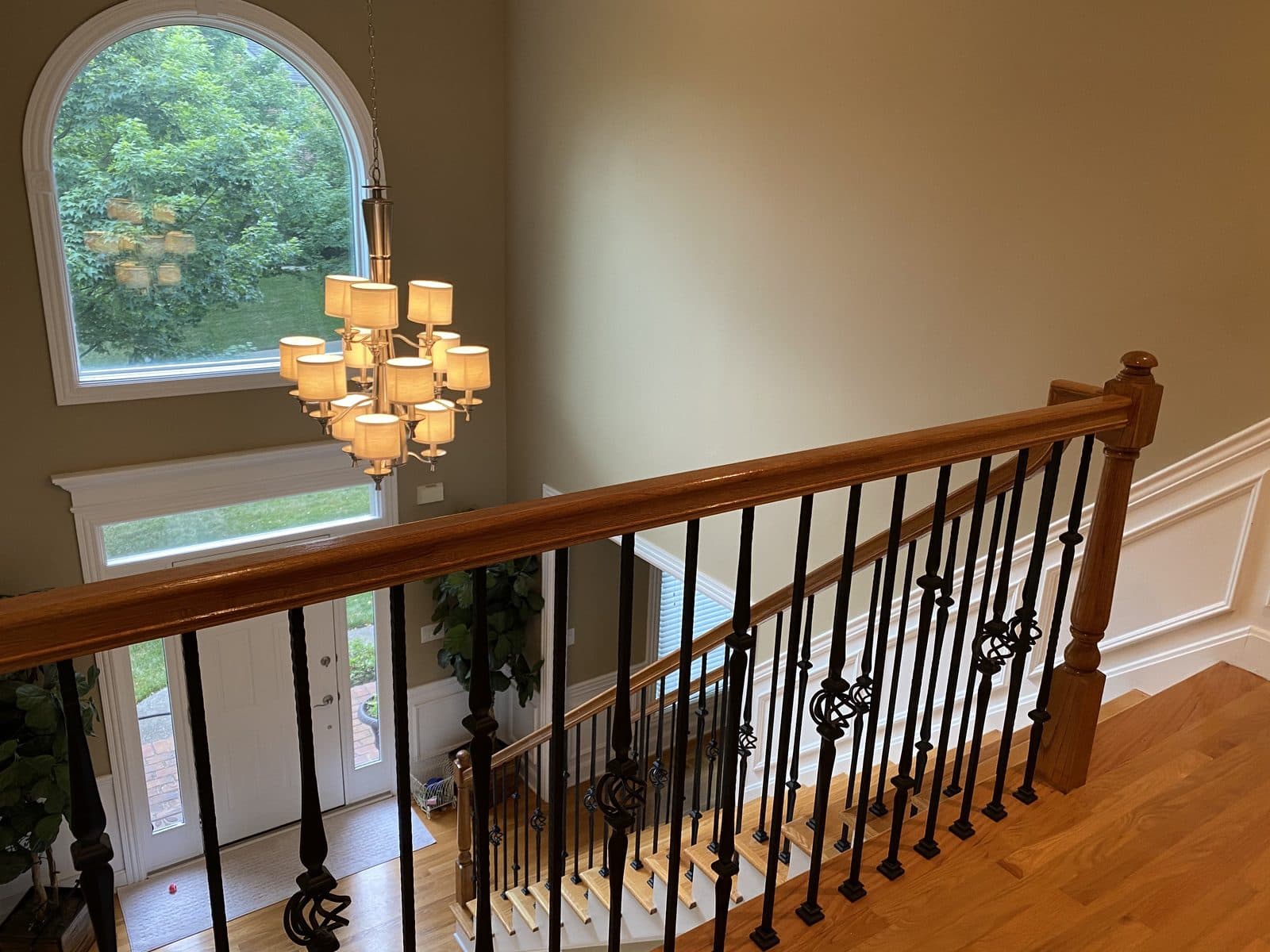 Looking down a curved staircase with a wooden handrail toward the front door of a family home.